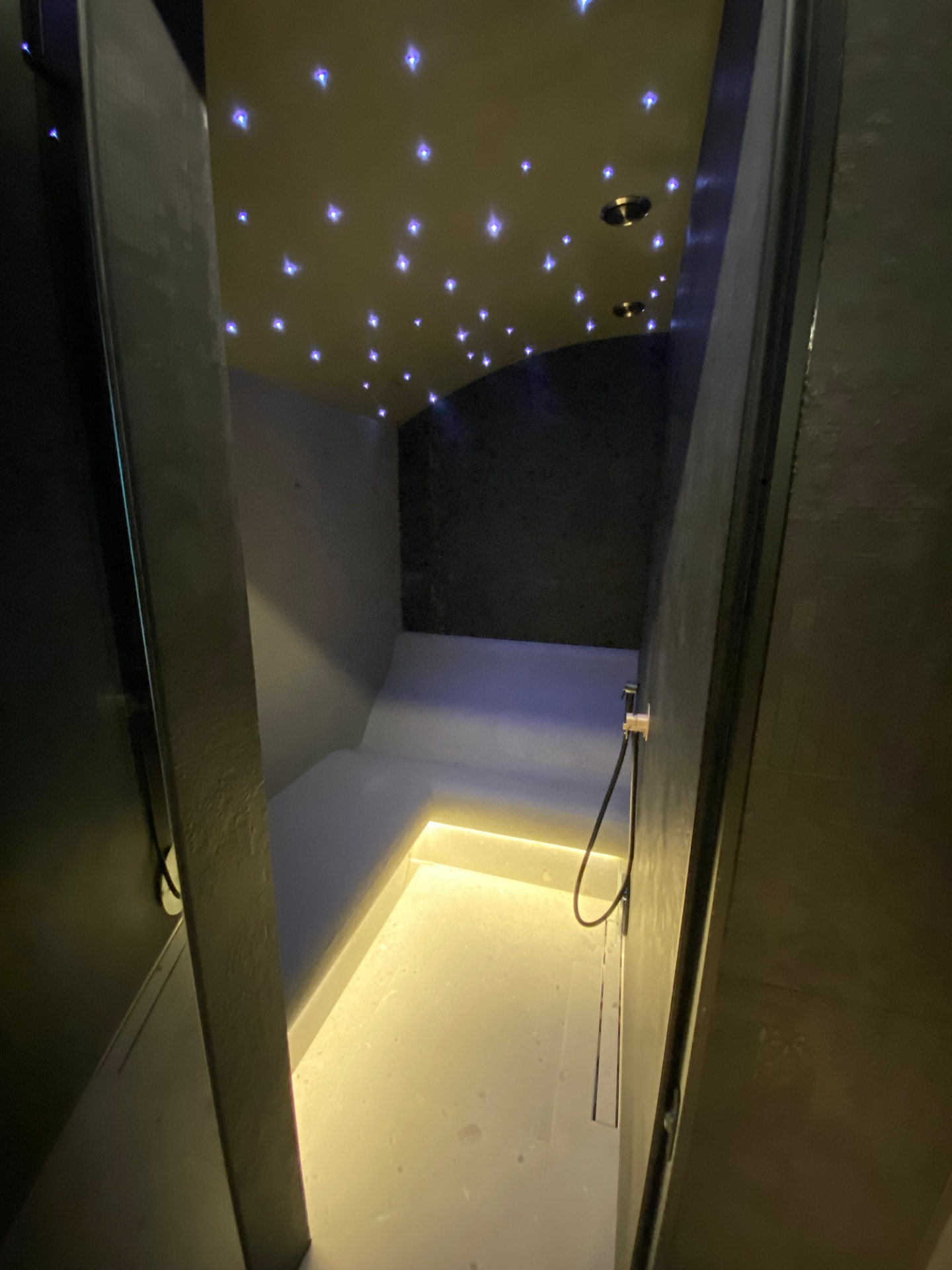 Dark steam room with starry ceiling and warm bench light